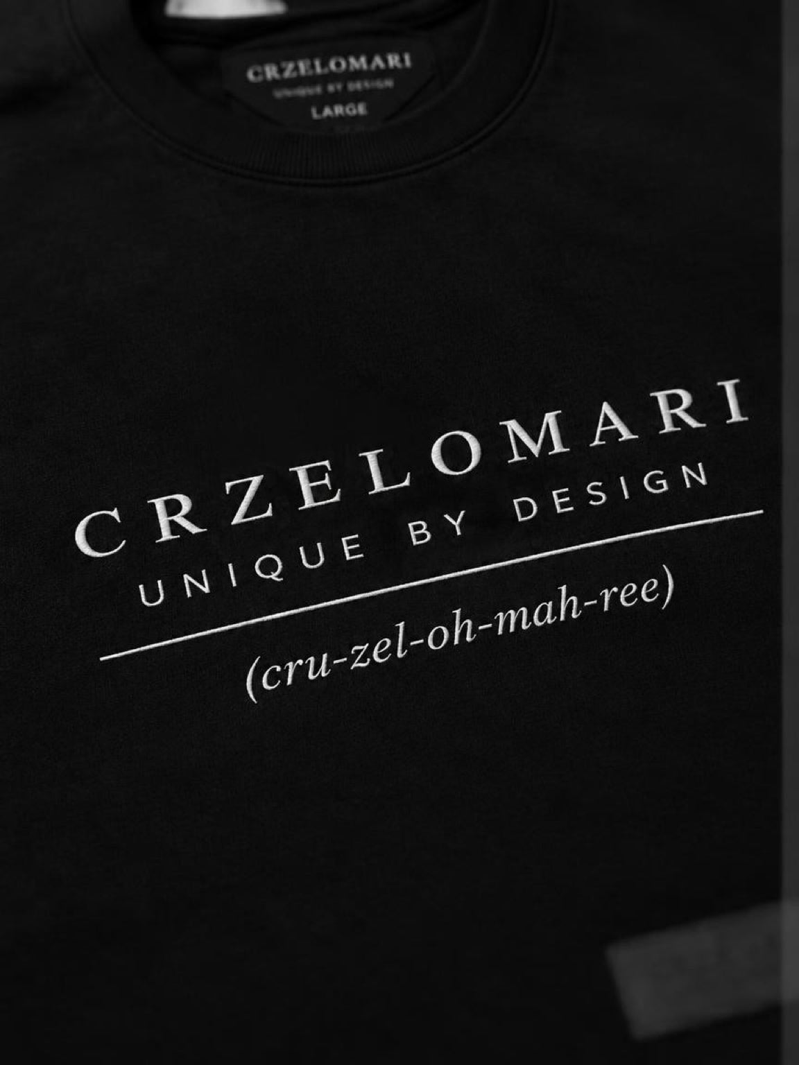Close-up of the CRZELOMARI Unique by Design front logo print on The Legacy Tee