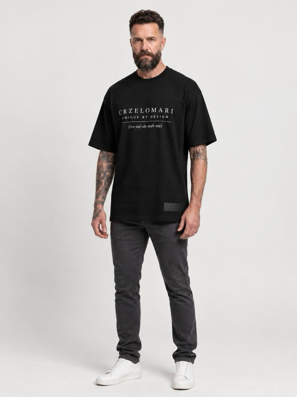 Tall man wearing The Legacy Tee, a black oversized T-shirt with the CRZELOMARI front logo