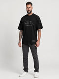 Tall man wearing The Legacy Tee, a black oversized T-shirt with the CRZELOMARI front logo