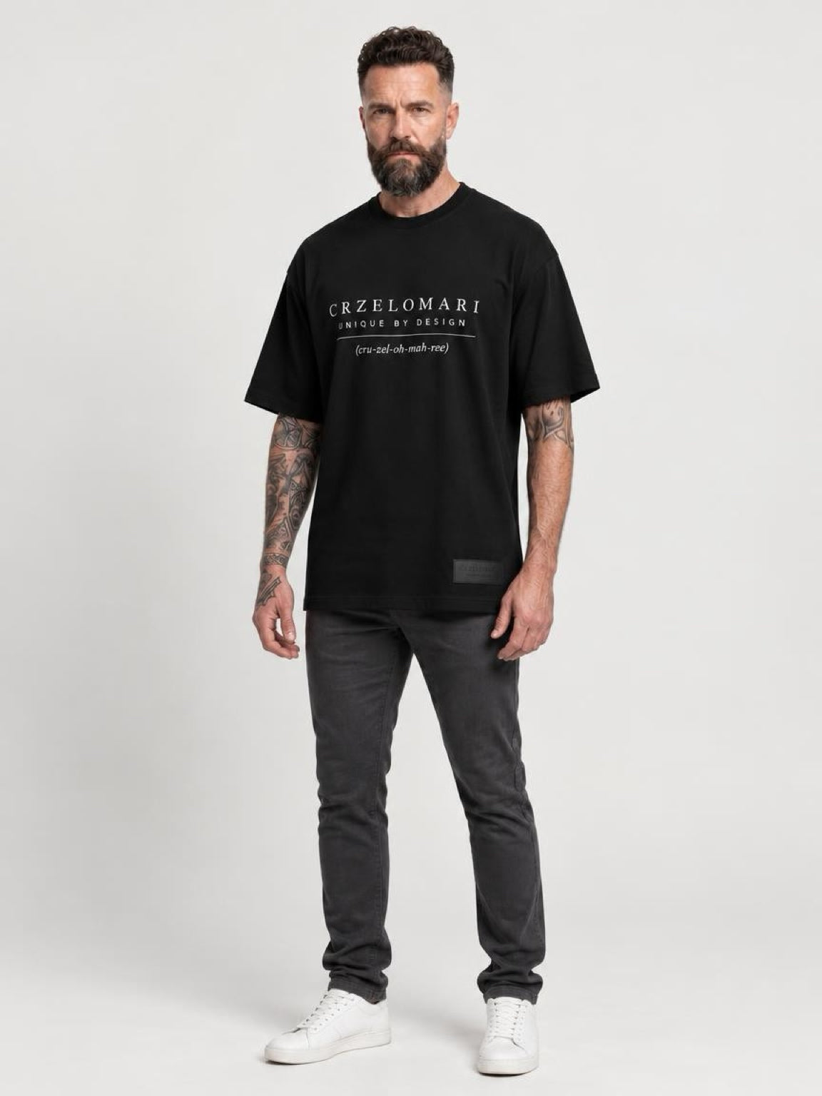 Tall man wearing The Legacy Tee, a black oversized T-shirt with the CRZELOMARI front logo